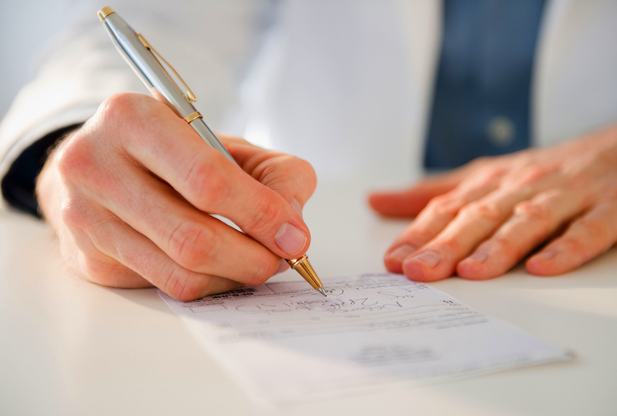 image of a doctor's hands, writing out a prescription