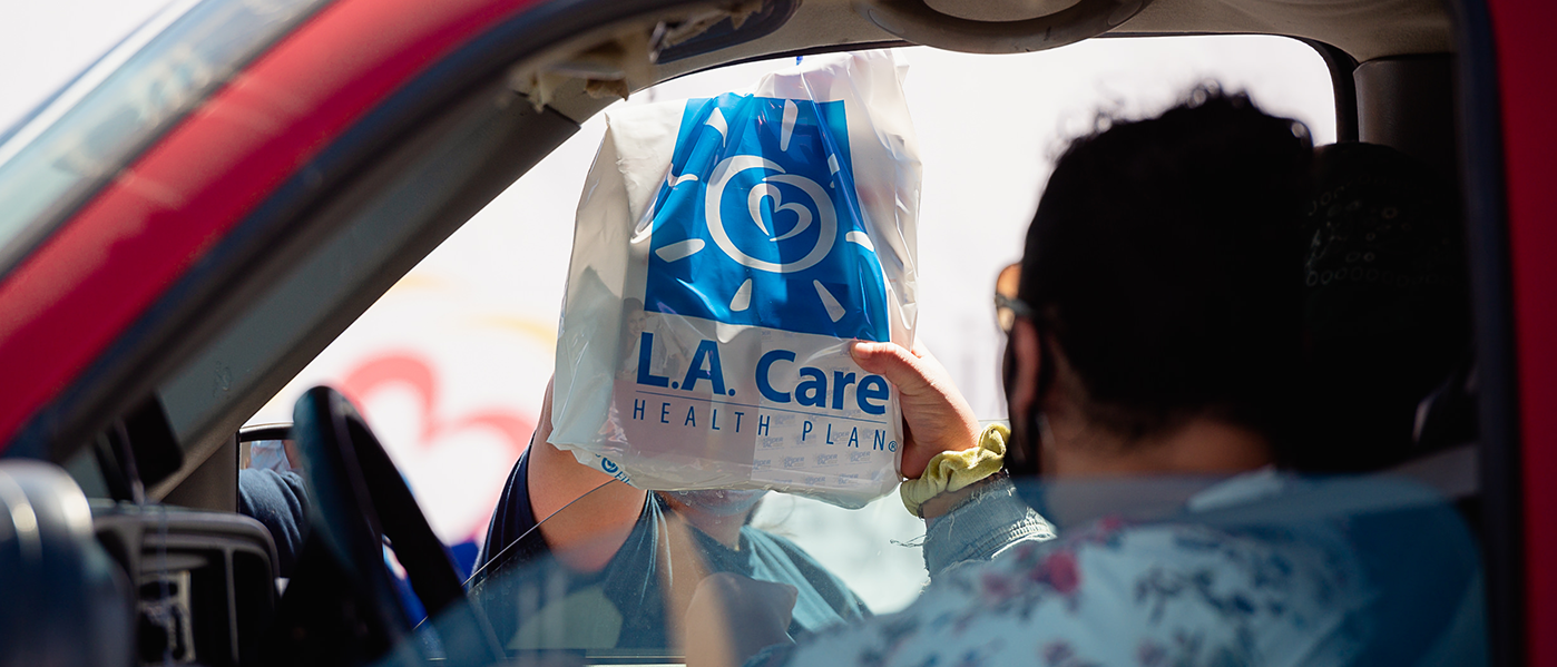 an L.A. Care bag handed to person in car