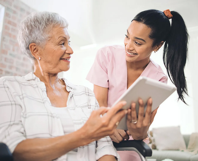 Young nurse sharing information from her digital tablet with an older woman in a wheelchair