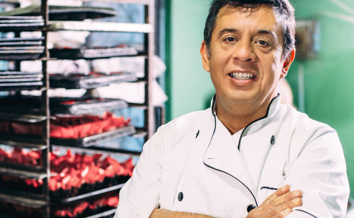 Baker in his kitchen with breads behind him