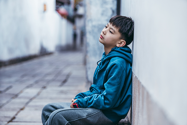 child sitting against a wall